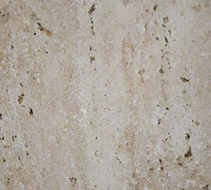 Primer plano de una superficie de piedra natural Travertino con textura beige con motas y vetas naturales.